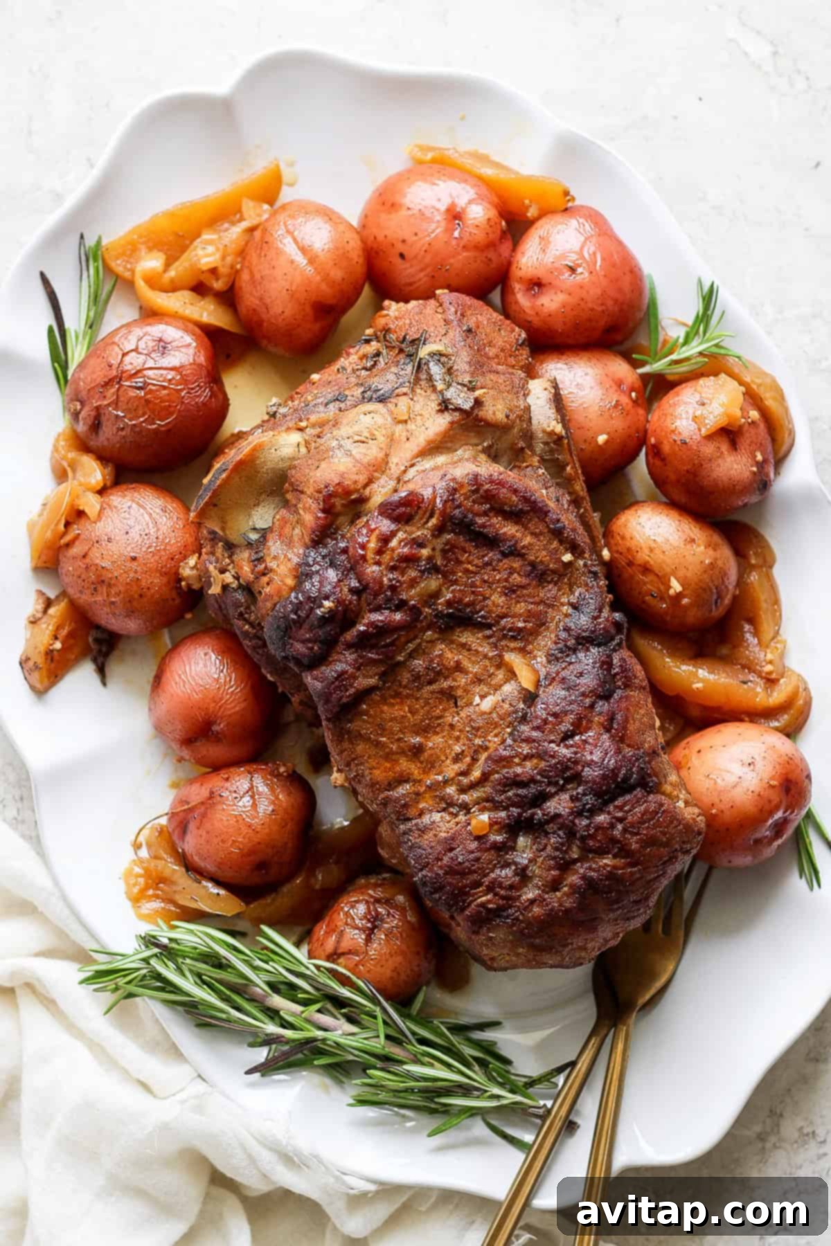 A beautifully roasted pork shoulder served on a clean white plate, artfully accompanied by tender red potatoes, caramelized onions, and garnished with fresh sprigs of rosemary. A white linen cloth adds a touch of elegance to the presentation.