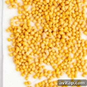 A large number of yellow chickpeas spread out on a white paper towel.