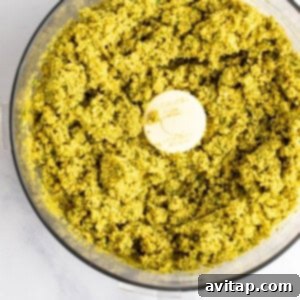 A food processor filled with blended green pesto.