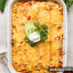 Creamy Cottage Cheese Taco Lasagna 13 A baked casserole topped with melted cheese, avocado slices, sour cream, and cilantro, presented in a white baking dish. Fresh jalapeños, cilantro, and a dish of red sauce are beside it.