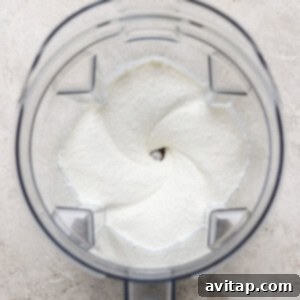 Top view of a clear blender jar containing a smooth, creamy white whipped cottage cheese mixture, essential for the high-protein taco lasagna.