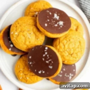 Chocolate Kissed Pumpkin Cookies 7 A plate of cookies, with some topped with a layer of chocolate and sea salt flakes, arranged on a white plate.