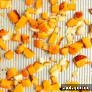 Diced butternut squash and chopped onions spread out and roasted on a baking sheet.
