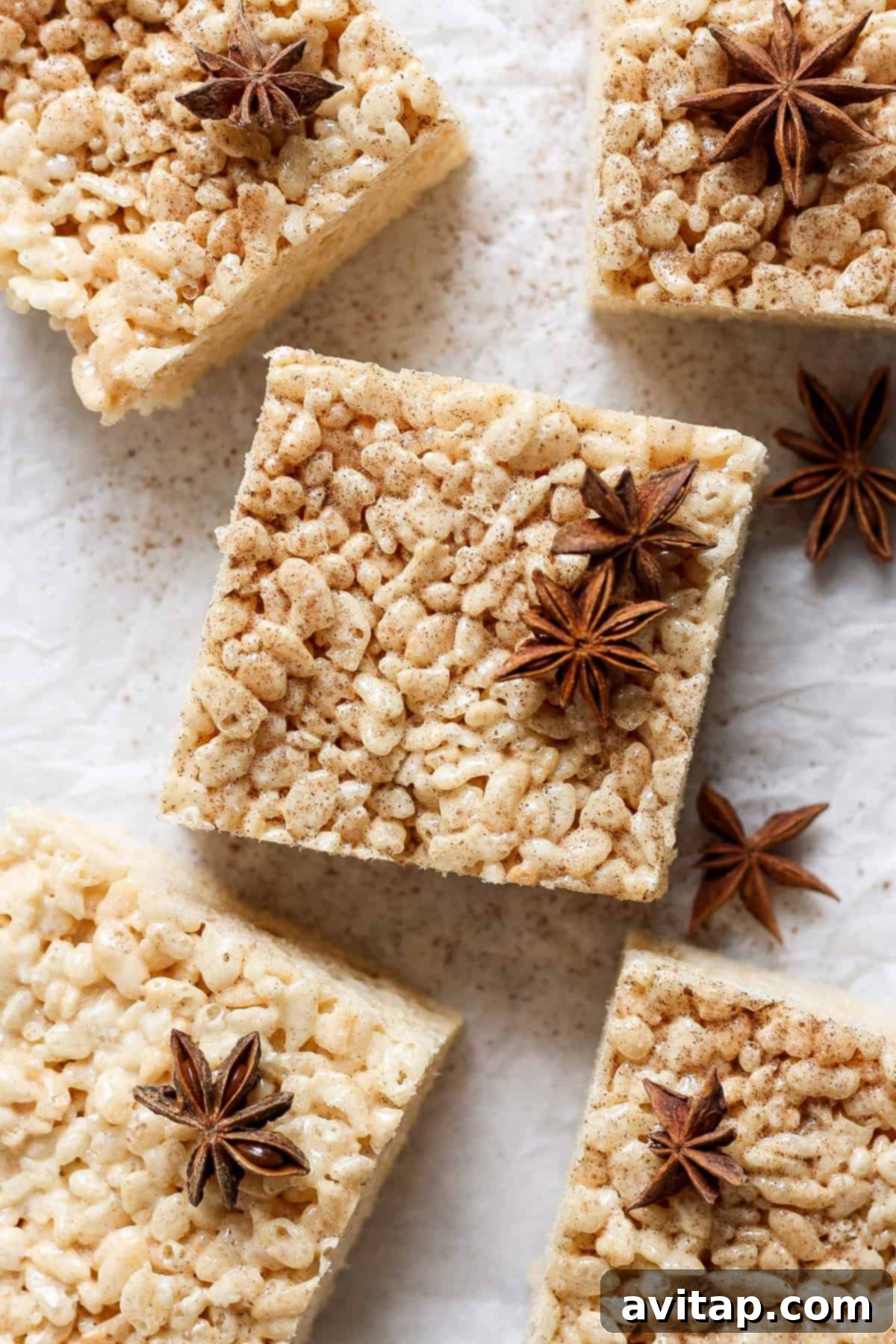Square brown butter chai rice krispie treats with a dusting of spices and garnished with star anise, arranged beautifully on a parchment paper surface.