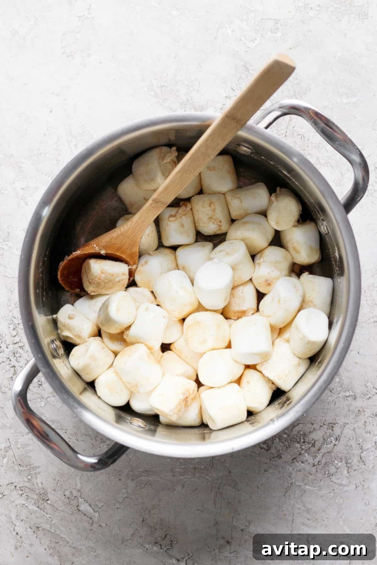 A pot filled with large marshmallows and a wooden spoon, ready to be melted for the rice krispie treats.