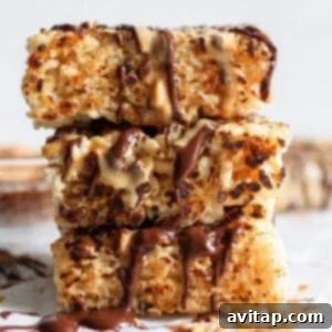 Stacked toasted rice krispie treats drizzled with chocolate and caramel sauces on a white surface, showcasing a golden, chewy texture.