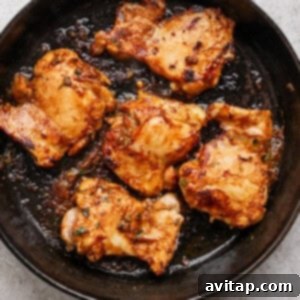 A cast-iron skillet contains five pieces of cooked, seasoned chicken, perfectly seared and ready for serving.