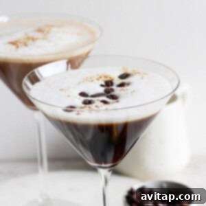 Two classic espresso martinis served in chic martini glasses, each boasting a frothy top and perfectly placed coffee bean garnish.