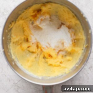 Mixing bowl with creamed butter and sugar on a textured surface.