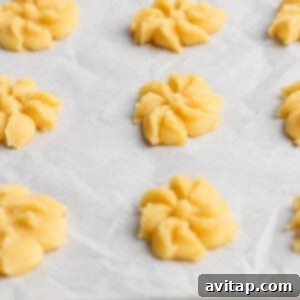 Raw cookie dough shaped into floral patterns on a parchment-lined baking sheet.
