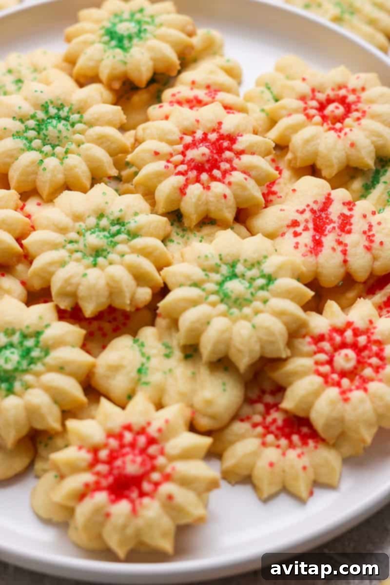 Mabel's Classic Spritz Cookies 7 A plate of flower-shaped cookies decorated with red and green sprinkles.