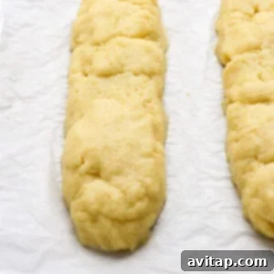 Two unbaked pastry dough logs on parchment paper, placed on a baking sheet.