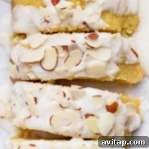 Sliced almond cake topped with white icing and sprinkled with almond slivers.