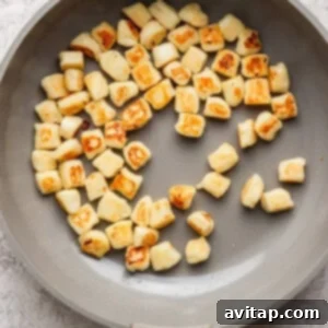 Pan with evenly browned gnocchi pieces on a light surface.