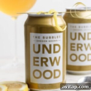 A can of Underwood The Bubbles wine from Oregon, transformed into a refreshing canned champagne cocktail, garnished with a lemon twist on a skewer.
