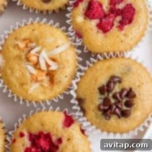 Assorted whipped cottage cheese muffins, beautifully topped with shredded coconut, dark chocolate chips, and fresh raspberries, presented in neat paper liners on a textured surface.
