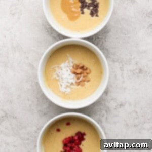 Three separate bowls of muffin batter, each topped with different mix-ins: one with chocolate chips and peanut butter, another with shredded coconut and nuts, and a third with vibrant red berries, ready to be folded in.