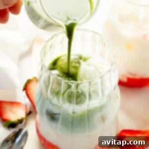 Strawberry Matcha Protein Refresher 10 Milk being poured into a glass with strawberries and green liquid.