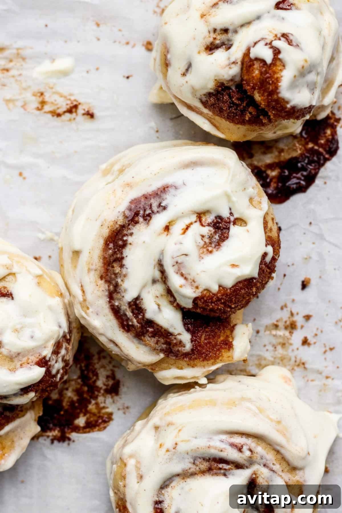 Protein-Rich Mini Cinnamon Rolls 4 Top-down view of four perfectly frosted small batch protein cinnamon rolls arranged on parchment paper, ready to be enjoyed.