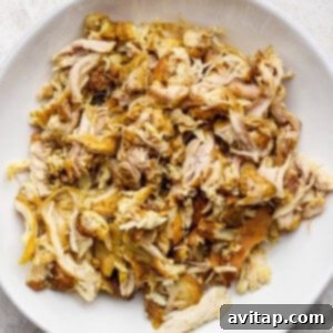 Curried Chicken Pot Pie 6 A white bowl filled with shredded, seasoned chicken on a textured surface.