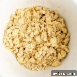 A bowl filled with a dry, crumbly mixture, commonly used for a crumble topping in baking, containing oats, flour, and butter.