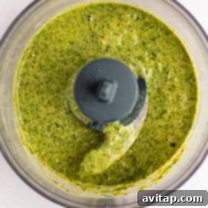 A vibrant green tarragon dressing in a food processor, perfectly blended to a smooth consistency, viewed from above.