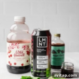 A bottle of tart cherry juice, a can of LMNT electrolyte drink, elderberry syrup, mint leaves, and lime slices on a white surface.