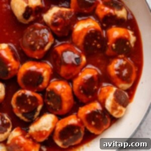 Sticky Sesame Ginger Salmon Meatballs 12 Meatballs in a skillet covered with a reddish-brown sauce.