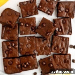 Sliced chocolate brownies with chocolate chips on top, arranged on a white surface.