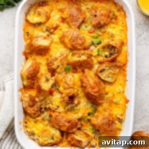 The fully baked croissant egg bake in a white dish, garnished with fresh herbs, alongside two glasses of orange juice.