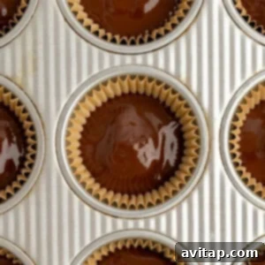 Muffin tin with cupcake liners, each filled with unbaked chocolate batter, ready to be chilled to set.