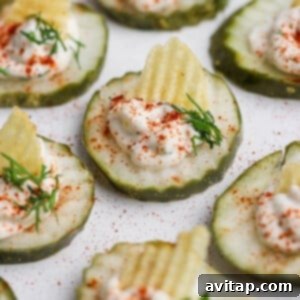 Cucumber slices topped with sour cream, a potato chip, dill, and paprika, arranged on a plate.