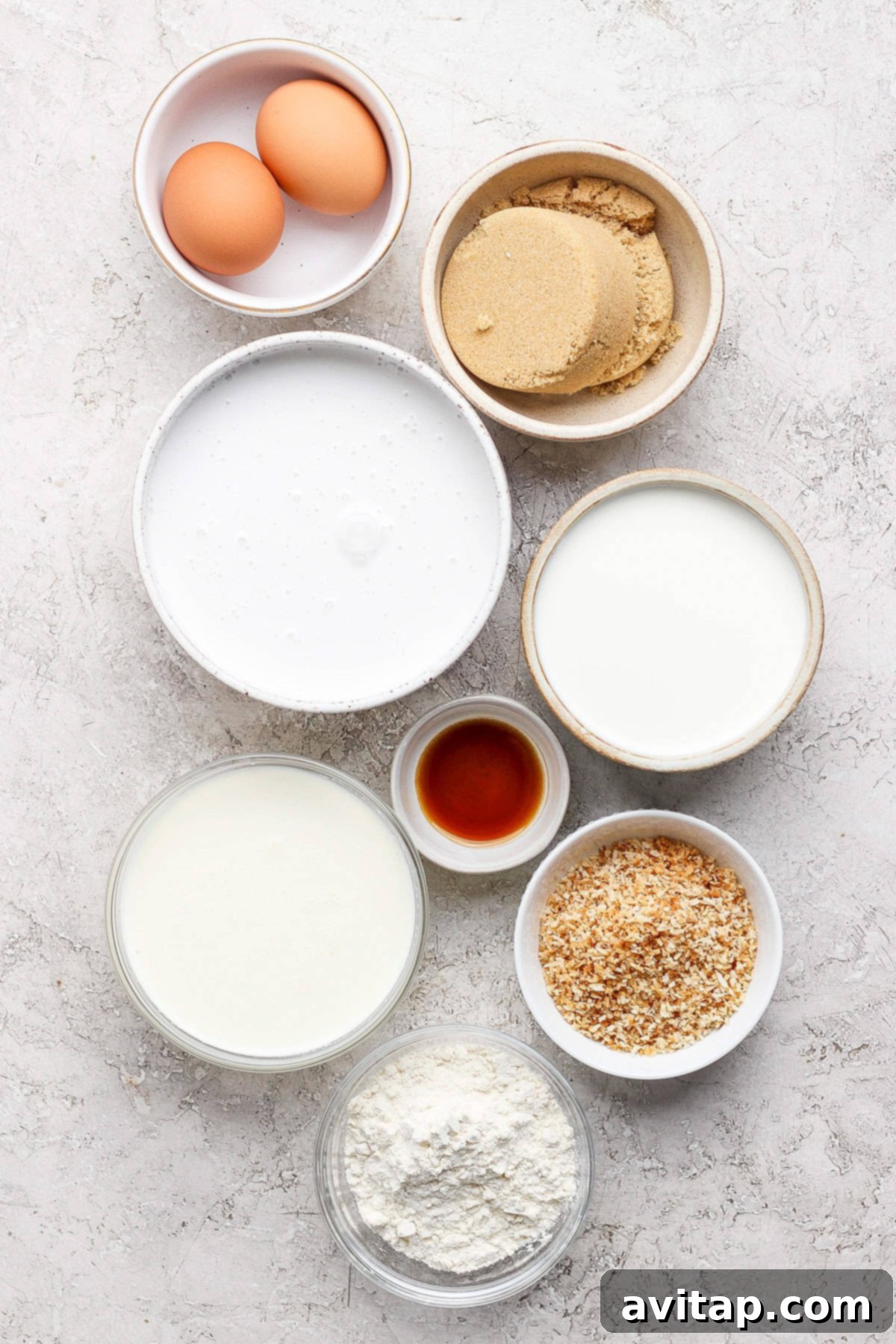 A vibrant collection of baking ingredients, including fresh eggs, golden brown sugar, white flour, rich vanilla extract, delicate coconut flakes, and creamy milk, artfully arranged on a clean, light-colored surface.