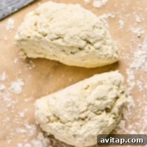Two pieces of dough sit on a floured surface next to a knife, ready to be transformed into homemade pizza pockets.
