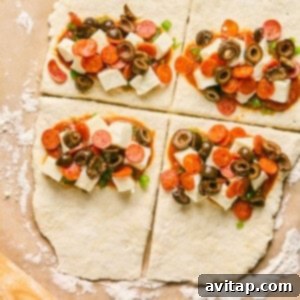 Four sections of raw dough, resembling pizza hot pockets, are topped with cheese cubes, pepperoni slices, olives, and green onions on a floured surface.