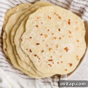 A beautifully arranged stack of homemade protein flatbreads resting on a vibrant striped kitchen towel, warm and ready to eat.