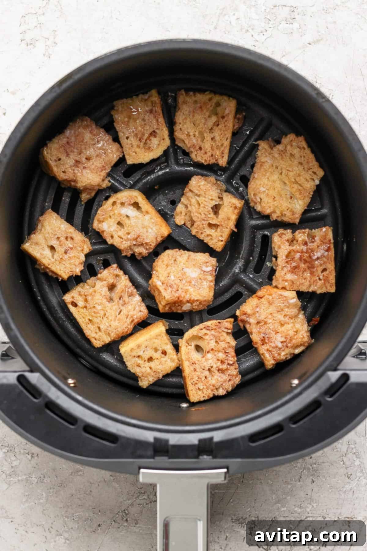 Pieces of cubed sourdough bread soaking in an egg and milk mixture in a large bowl, ready for air frying.