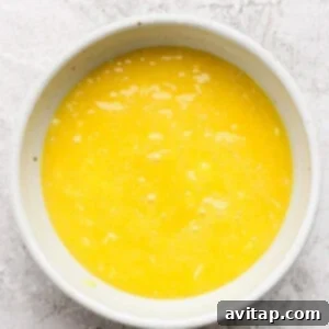 A white bowl filled with beaten eggs on a textured white surface.