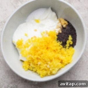 A bowl containing blended cottage cheese, lemon zest, honey, chia seeds, and other ingredients for the chia pudding on a light-colored surface, ready for mixing.