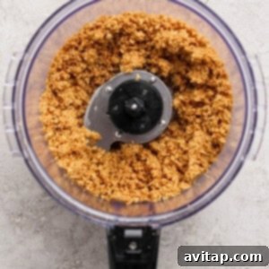 A food processor containing a mixture of finely ground ingredients on a light textured surface.
