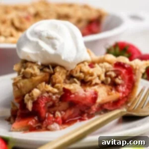 A delicious slice of strawberry apple pie crumble topped with a swirl of fresh whipped cream, presented elegantly on a white plate with vibrant fresh strawberries scattered in the background, showcasing the dessert's appealing texture and color.