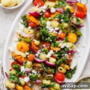 Grilled Rainbow Gnocchi Pops 12 A white platter with vegetable and gnocchi skewers, topped with chopped herbs and crumbled cheese, is pictured next to small bowls of cooked gnocchi and crumbled cheese.