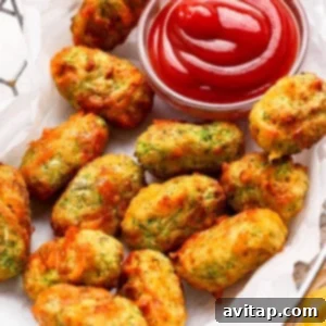 A basket of baked vegetable tots served with a small bowl of ketchup for dipping.
