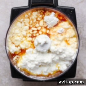 A food processor bowl filled with the smooth, creamy cottage cheese, maple syrup, cornstarch, and vanilla mixture, perfectly blended for the cheesecake filling.