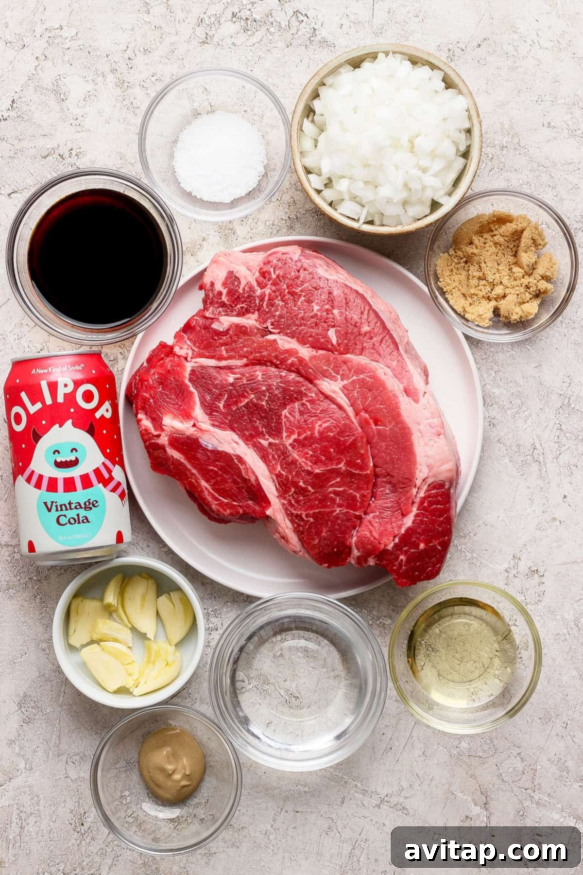 OLIPOP Infused Chuck Roast 3 Raw chuck roast on a pristine white plate, surrounded by an array of small white bowls containing the marinade ingredients: finely chopped onions, rich brown sugar, minced garlic cloves, coarse salt, apple cider vinegar, tangy Dijon mustard, clear cooking oil, savory soy sauce, and a vibrant can of OLIPOP Vintage Cola, all arranged on a light-colored surface, ready for marination.