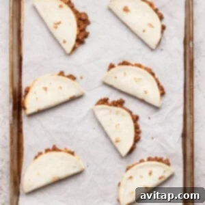 Six folded and baked sheet pan tacos, golden brown and crispy, arranged neatly on a parchment-lined baking sheet, fresh out of the oven.