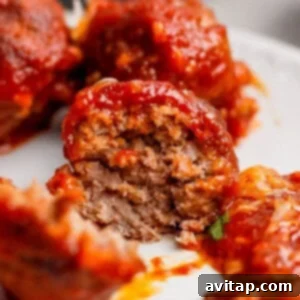 Hearty Sloppy Joe Meatballs 5 A close-up of a partially eaten meatball covered in tomato sauce, revealing its cooked, ground meat interior.