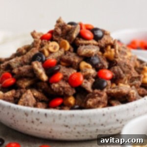 A beautifully arranged bowl filled with chocolate-coated Chex cereal, topped generously with orange and brown M&M’s and glistening butterscotch chips, ready to be enjoyed.