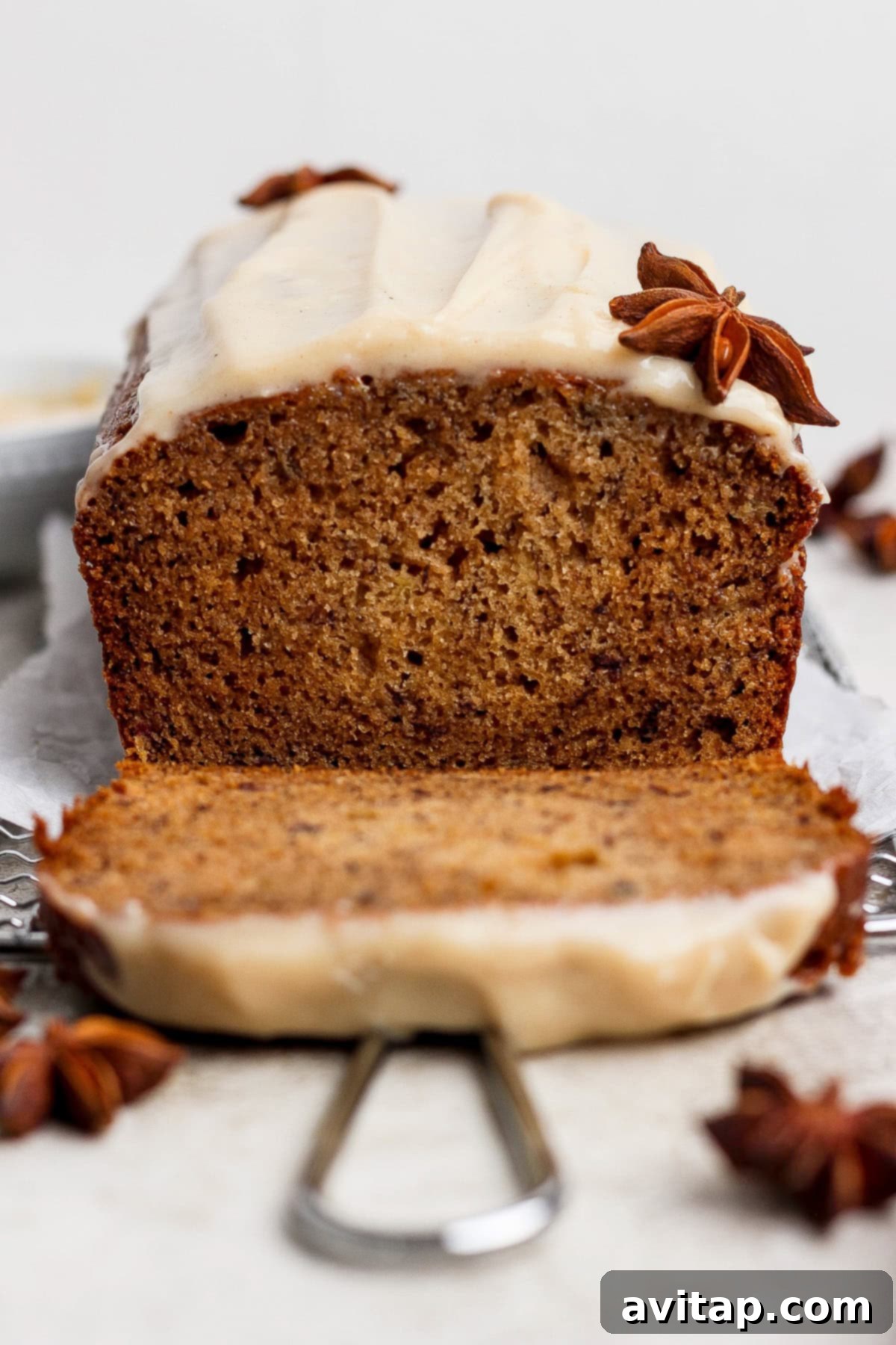 Chai-Spiced Brown Butter Banana Bread 2 A loaf of spiced banana bread is sliced, topped with a light frosting and star anise decorations placed on and around the bread—a delicious twist on a classic banana bread recipe.