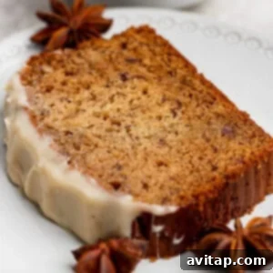 A slice of moist spiced bread from our favorite banana bread recipe, topped with white icing on one end and served on a white plate with star anise for garnish.